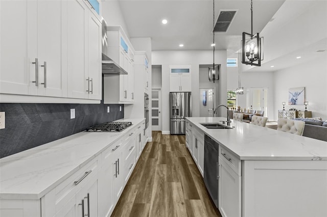 kitchen with a large island, sink, white cabinets, and hanging light fixtures