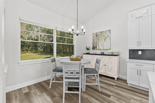 dining space featuring an inviting chandelier, wood-type flooring, and vaulted ceiling