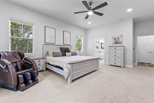 carpeted bedroom featuring ceiling fan, multiple windows, and ensuite bath