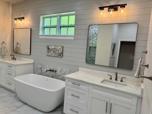 4586 Hickory Oak Dr, Brooksville, FL 34601 - bathroom featuring wooden walls, marble finish floors, two vanities, and a soaking tub
