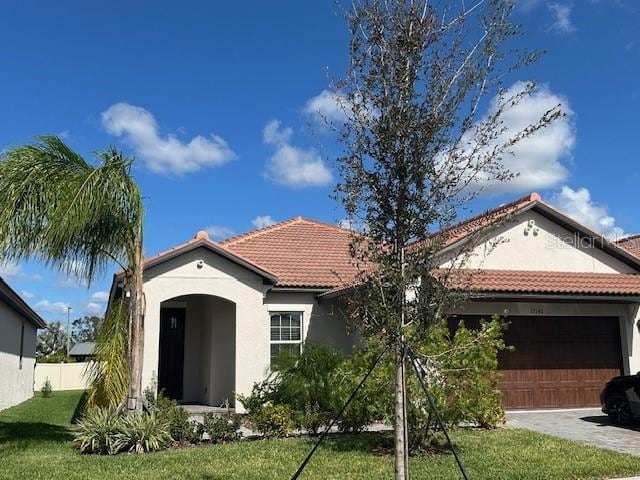 mediterranean / spanish-style house featuring a garage and a front lawn