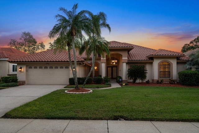 mediterranean / spanish-style house with a yard and a garage