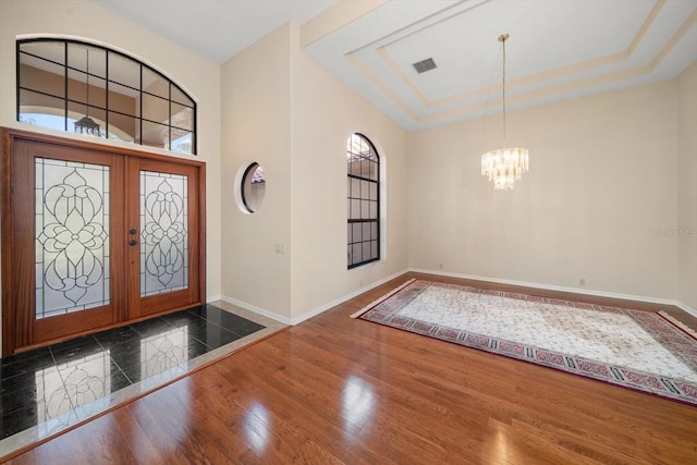 entryway featuring an inviting chandelier, french doors, a tray ceiling, and dark hardwood / wood-style flooring