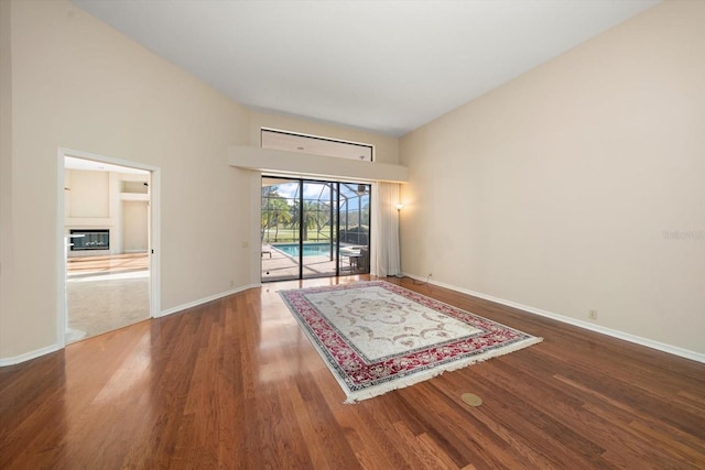 spare room featuring wood-type flooring and a towering ceiling