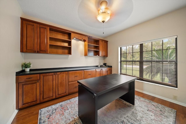 home office featuring ceiling fan, a textured ceiling, and dark hardwood / wood-style flooring