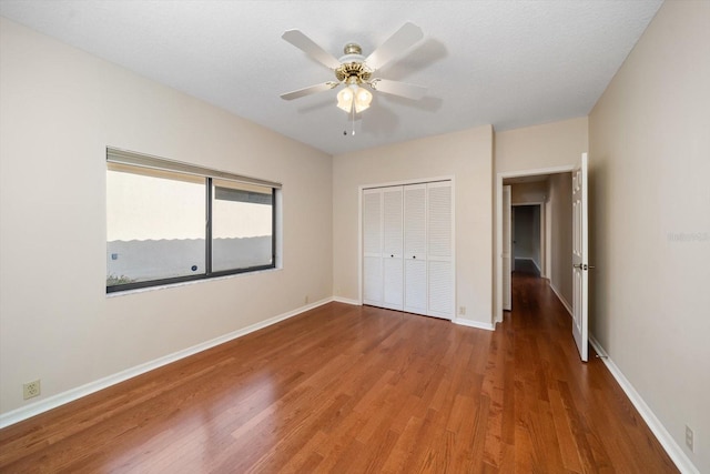 unfurnished bedroom with a textured ceiling, wood-type flooring, a closet, and ceiling fan