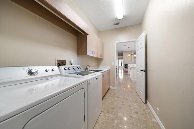 laundry area featuring cabinets, a textured ceiling, sink, and separate washer and dryer