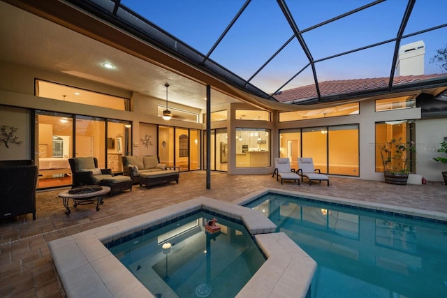 back house at dusk featuring a patio area, a pool with hot tub, a lanai, and an outdoor hangout area