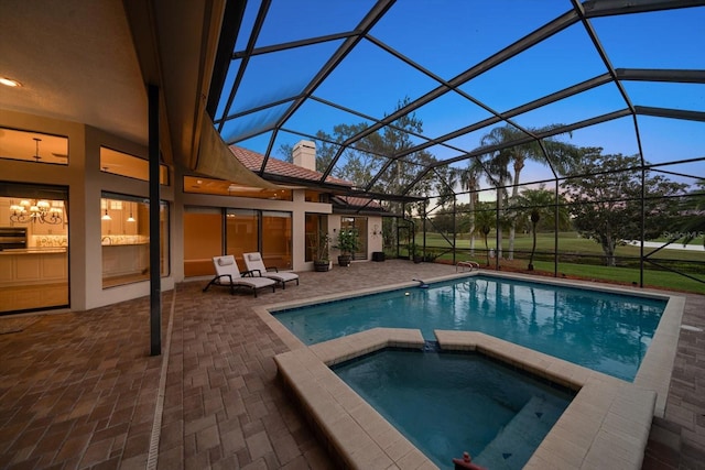 pool at dusk featuring an in ground hot tub, a patio area, and a lanai