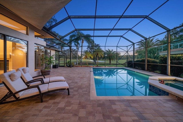 pool at dusk featuring a patio area, a lanai, and an in ground hot tub