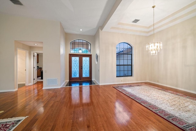 entryway with french doors, wood-type flooring, and an inviting chandelier