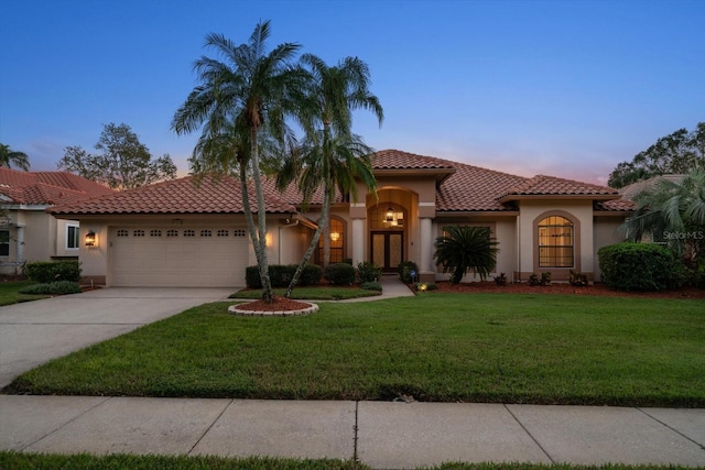 mediterranean / spanish-style house with a garage and a lawn