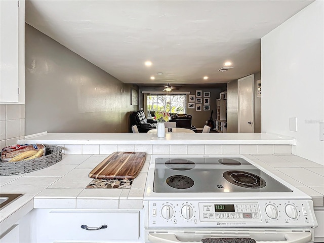 kitchen featuring tile countertops, white cabinetry, and range