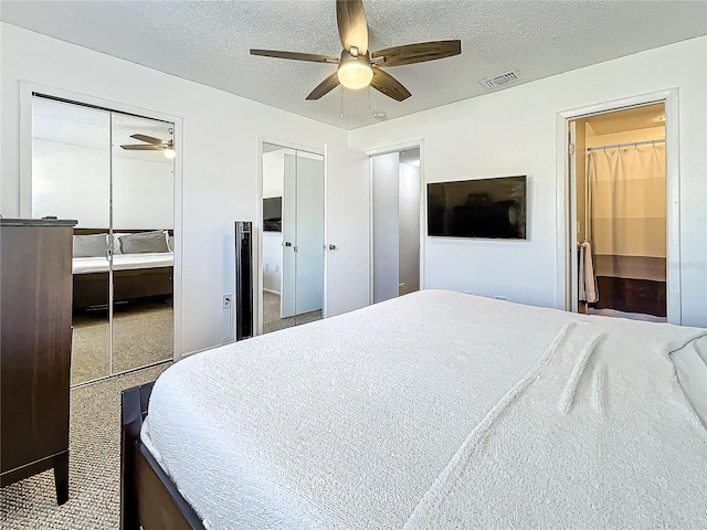 bedroom featuring a textured ceiling, ceiling fan, and two closets