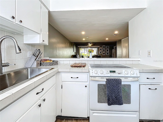 kitchen featuring white cabinets, sink, electric range, decorative backsplash, and kitchen peninsula