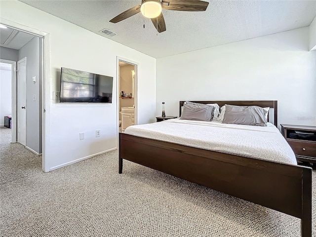 bedroom with a textured ceiling, ceiling fan, light carpet, and connected bathroom