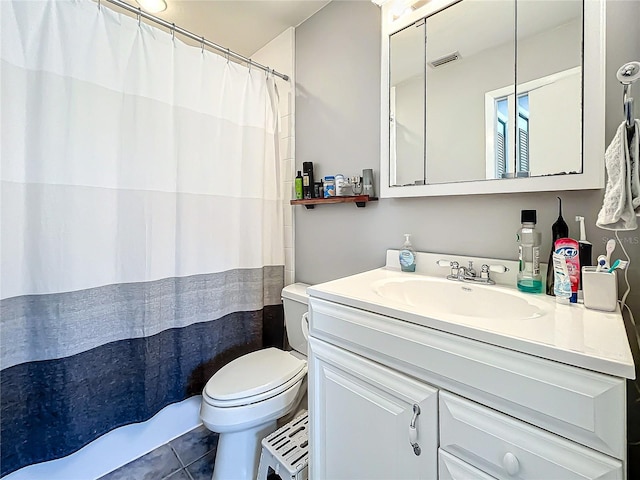 bathroom featuring tile patterned flooring, vanity, toilet, and walk in shower