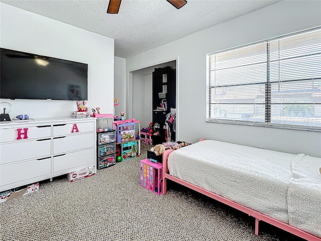 carpeted bedroom featuring ceiling fan and a textured ceiling