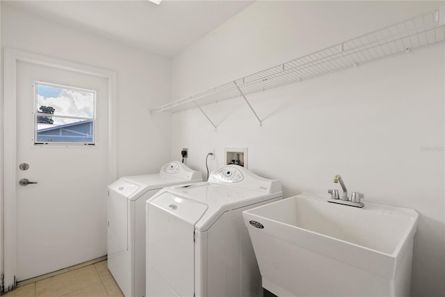 clothes washing area with light tile patterned floors, washing machine and dryer, and sink