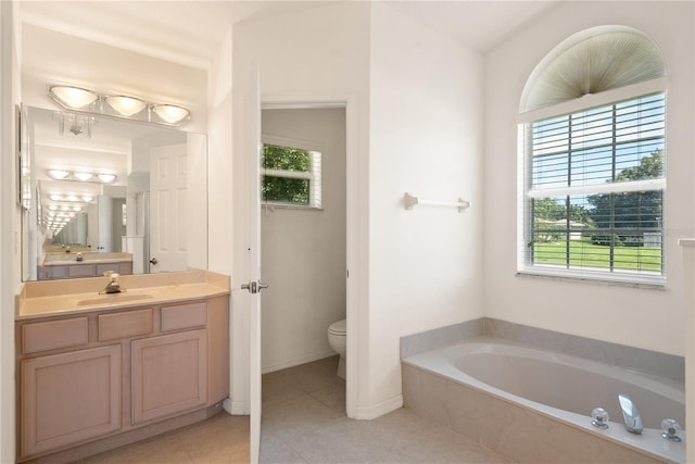 bathroom featuring vanity, tiled bath, toilet, and plenty of natural light