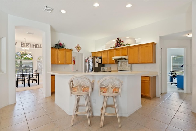 kitchen featuring an inviting chandelier, stainless steel fridge, a center island, and light tile patterned floors