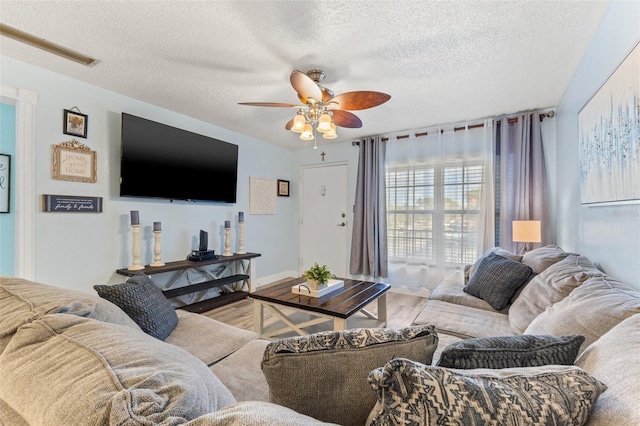 living room with hardwood / wood-style flooring, ceiling fan, and a textured ceiling