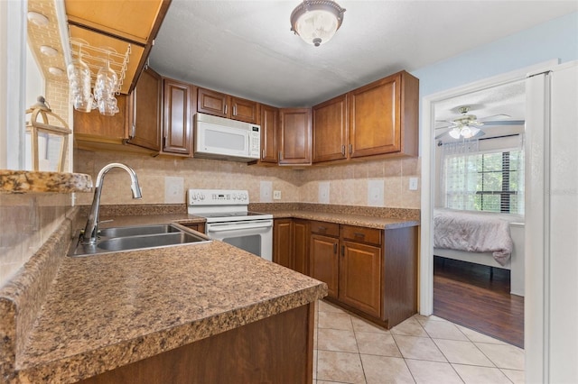 kitchen featuring sink, white appliances, light tile patterned floors, ceiling fan, and decorative backsplash