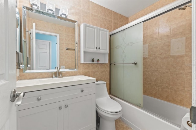 full bathroom featuring vanity, tile walls, shower / bath combination with glass door, and toilet