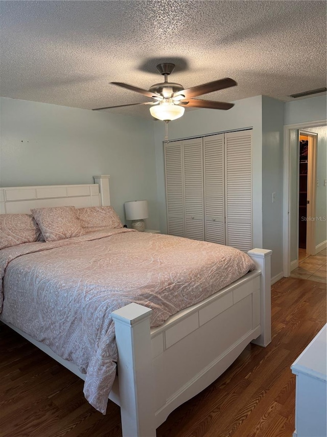 bedroom with ceiling fan, dark hardwood / wood-style floors, a textured ceiling, and a closet