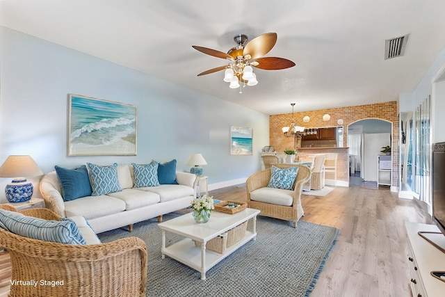 living room with ceiling fan with notable chandelier and light hardwood / wood-style flooring