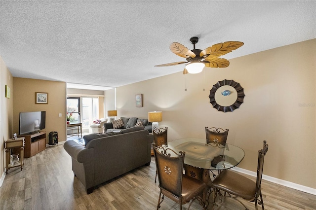 dining room featuring ceiling fan, hardwood / wood-style flooring, and a textured ceiling