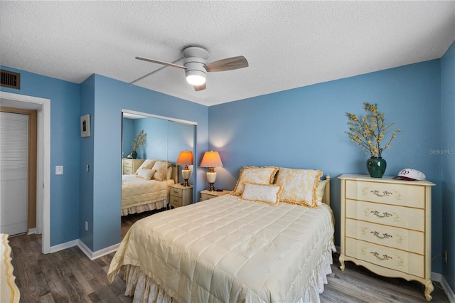 bedroom featuring dark wood-type flooring, a textured ceiling, and ceiling fan