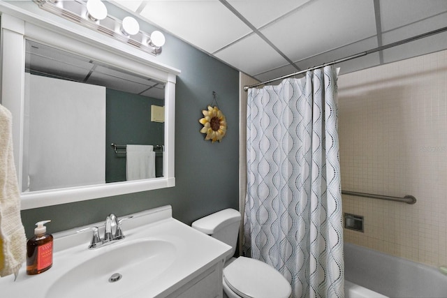 full bathroom featuring toilet, a drop ceiling, vanity, and shower / tub combo