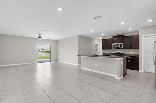 kitchen featuring ceiling fan, a kitchen island with sink, white stove, dark brown cabinetry, and sink