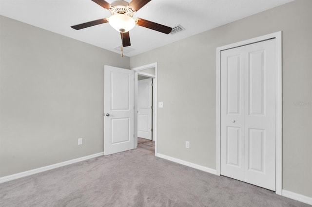 unfurnished bedroom featuring a closet, light colored carpet, and ceiling fan