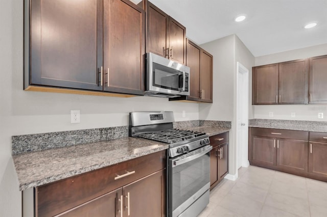 kitchen featuring light stone countertops, appliances with stainless steel finishes, and dark brown cabinets