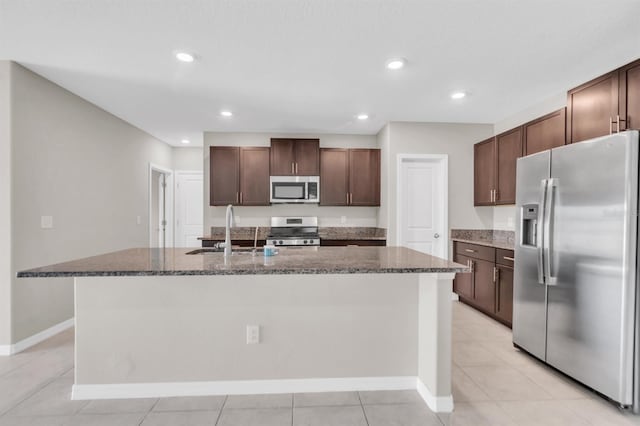 kitchen featuring appliances with stainless steel finishes, sink, an island with sink, dark brown cabinetry, and light tile patterned floors