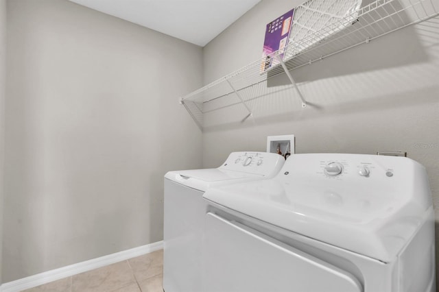 laundry area with washing machine and dryer and light tile patterned floors