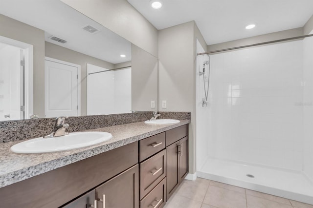 bathroom with vanity, a tile shower, and tile patterned flooring