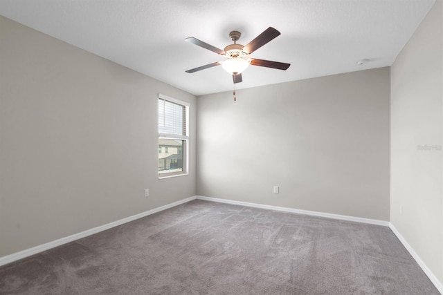 empty room with ceiling fan and dark colored carpet