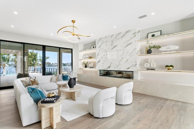 living room with light hardwood / wood-style floors, a premium fireplace, and a chandelier