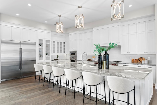 kitchen featuring pendant lighting, appliances with stainless steel finishes, sink, and a large island with sink