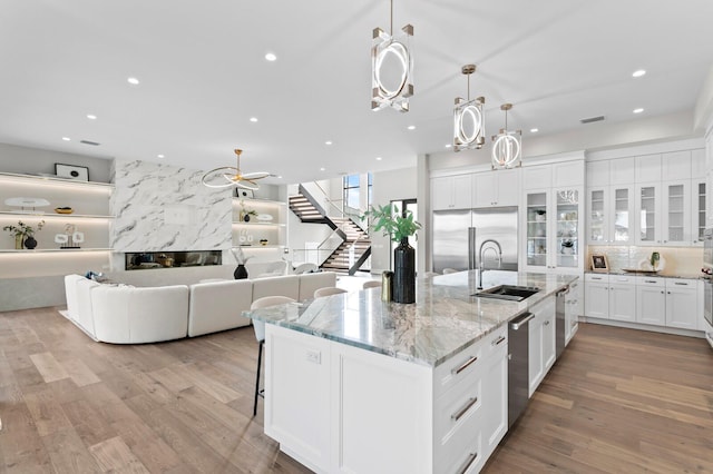 kitchen featuring sink, stainless steel appliances, a spacious island, white cabinets, and decorative light fixtures