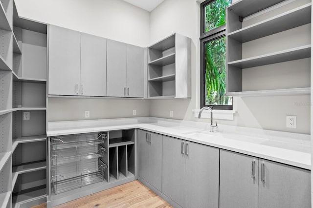 kitchen with gray cabinets, sink, and light wood-type flooring