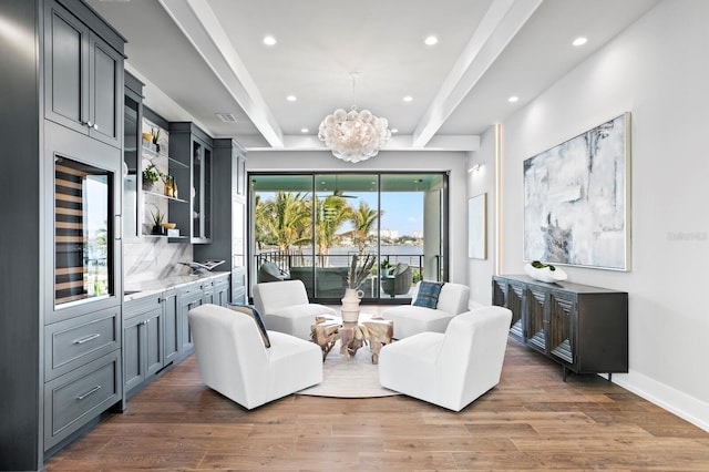 living area with wine cooler, a notable chandelier, beam ceiling, and dark wood-type flooring