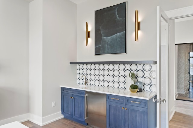 bar featuring tasteful backsplash, wood-type flooring, and blue cabinetry