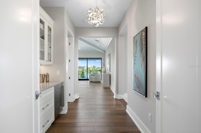 corridor with lofted ceiling, dark wood-type flooring, and a chandelier