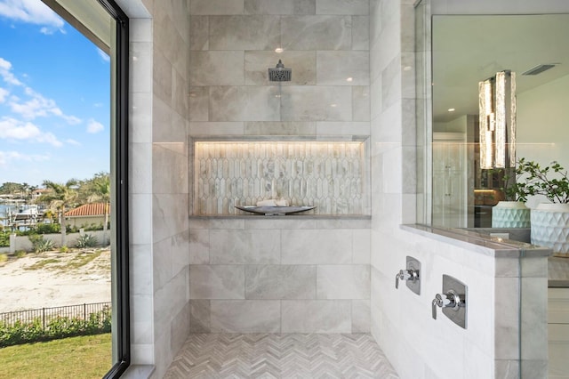 bathroom with tiled shower and plenty of natural light