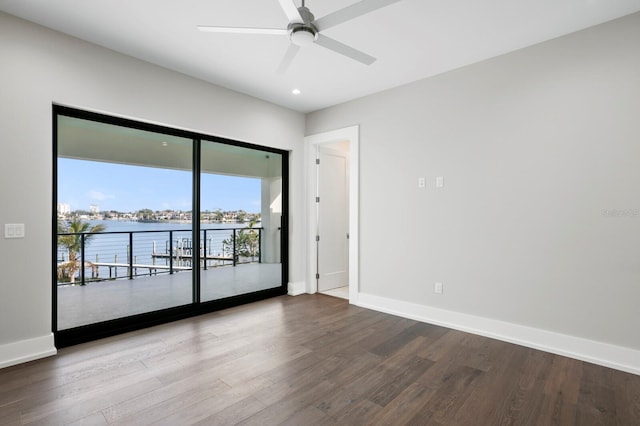 spare room with hardwood / wood-style flooring, a water view, and ceiling fan