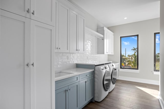 clothes washing area with cabinets, dark hardwood / wood-style floors, sink, and washer and clothes dryer